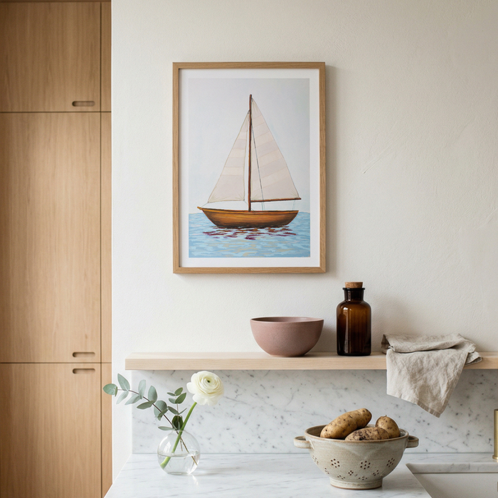 Framed sailboat artwork on a wall above a kitchen counter with various items.