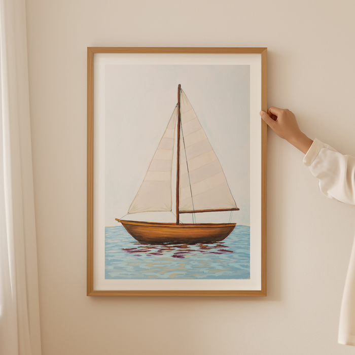 Framed artwork of a sailboat on a wall with a hand adjusting the frame.